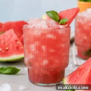 A glass of a refreshing Watermelon Basil Cocktail, garnished with fresh basil and a watermelon wedge, showcasing its vibrant color.