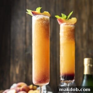 A picture of two luscious Frozen Peach Bellinis in tall glasses, garnished with fresh fruit, appearing cool and inviting.