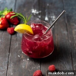 An image of a Berry Vodka Smash cocktail, garnished with fresh berries and rosemary, in a elegant glass.