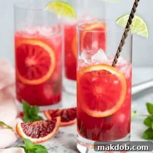 An image of three glasses filled with vibrant Blood Orange Mojitos, garnished with mint and blood orange slices.