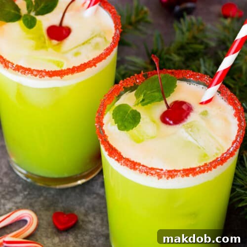 Cups of Grinch punch topped with cherries and mint sprigs.