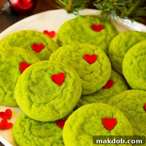 A plate of Grinch cookies with heart sprinkles on top of them.