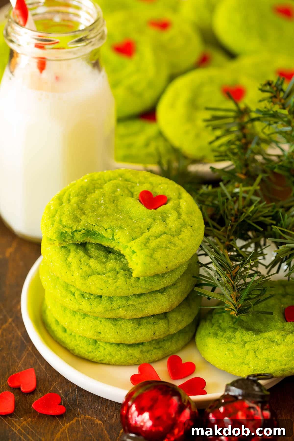 Merry Grinchmas Cookies 6 A stack of vibrant green Grinch cookies, one with a bite taken out, showcasing the soft and chewy interior.