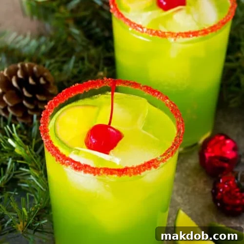 Stolen Holiday Spirit 7 Two cups of Grinch cocktail garnished with cherries and limes.