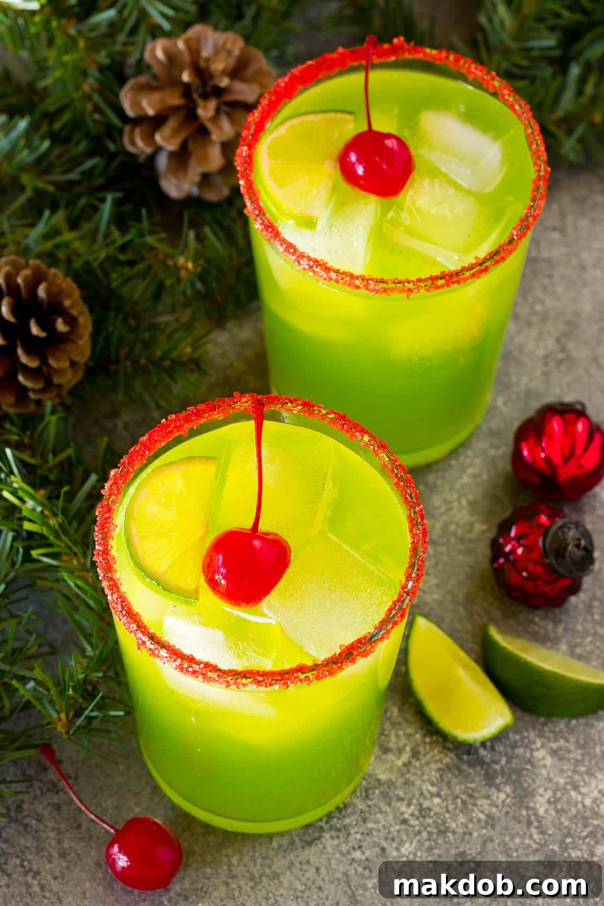 Stolen Holiday Spirit 6 Grinch cocktail in a serving glass with a red sugar rim and maraschino cherry on top.