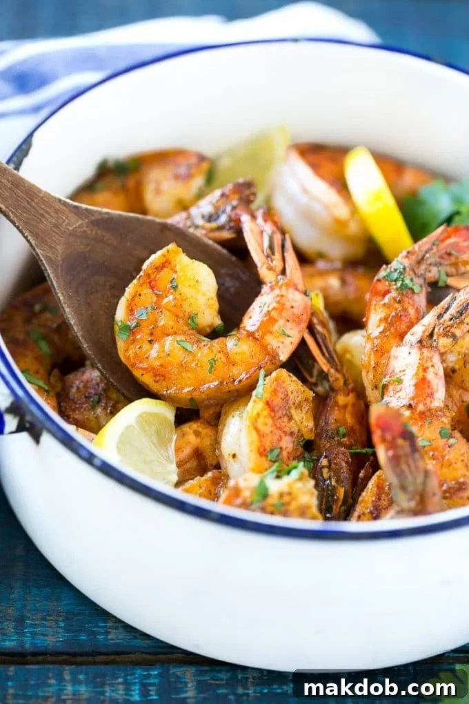 New Orleans BBQ Shrimp | Barbecue Shrimp #shrimp #seafood #dinner #appetizer #dinneratthezoo A wooden spoon serving up a portion of New Orleans BBQ shrimp, showcasing the rich sauce and perfectly cooked shrimp.