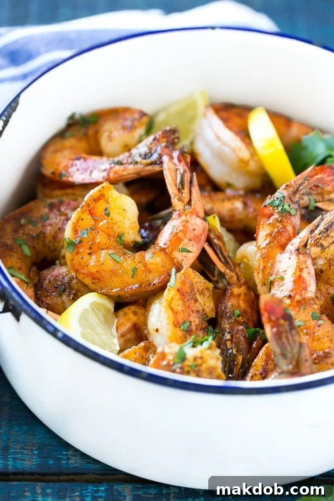 New Orleans BBQ Shrimp | Barbecue Shrimp #shrimp #seafood #dinner #appetizer #dinneratthezoo A pot of New Orleans BBQ shrimp garnished with fresh lemon wedges and vibrant parsley, ready to be served.