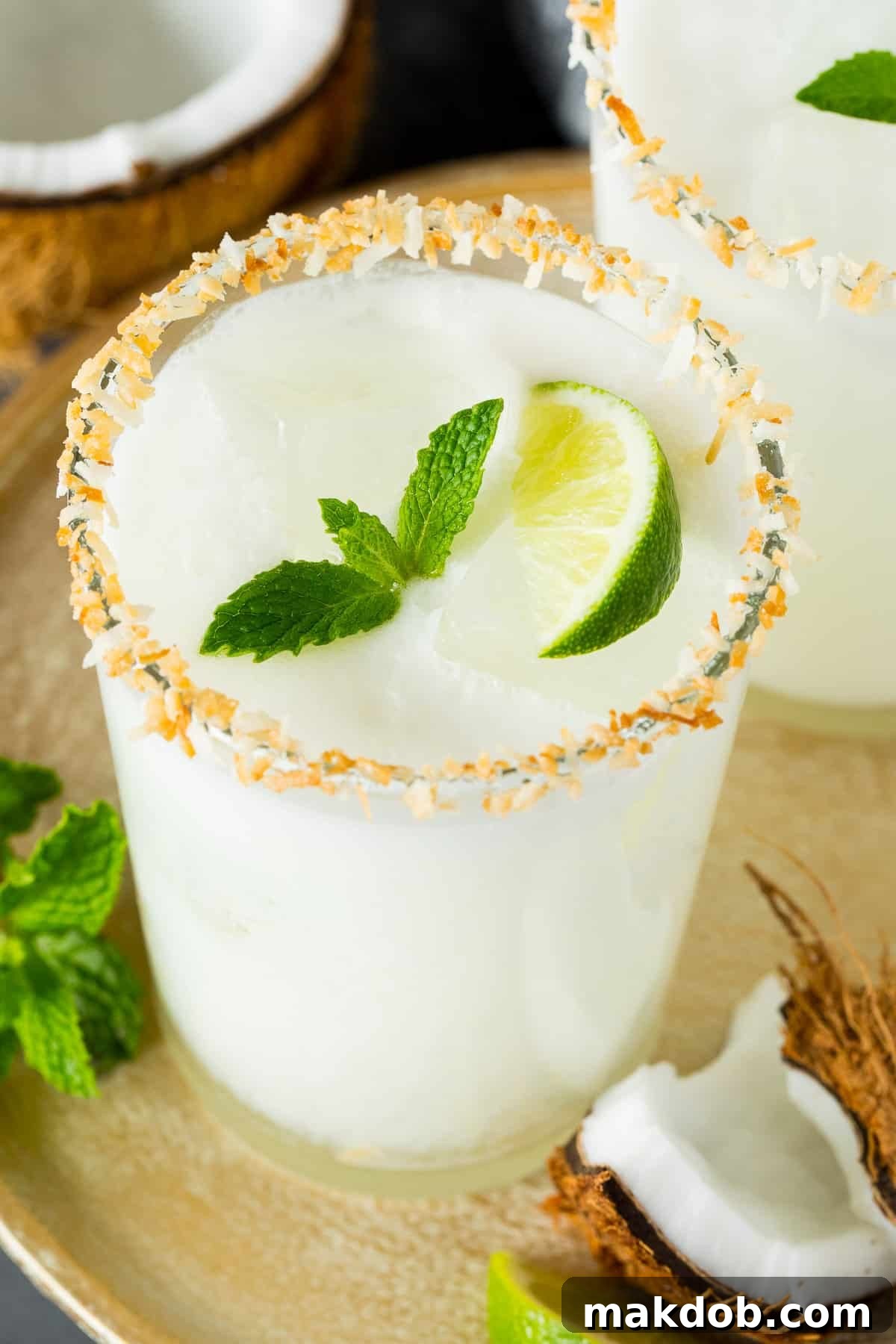 Paradise Coconut Margarita 2 A beautifully presented glass of coconut margarita with a toasted coconut rim and a fresh mint garnish, ready to be enjoyed.
