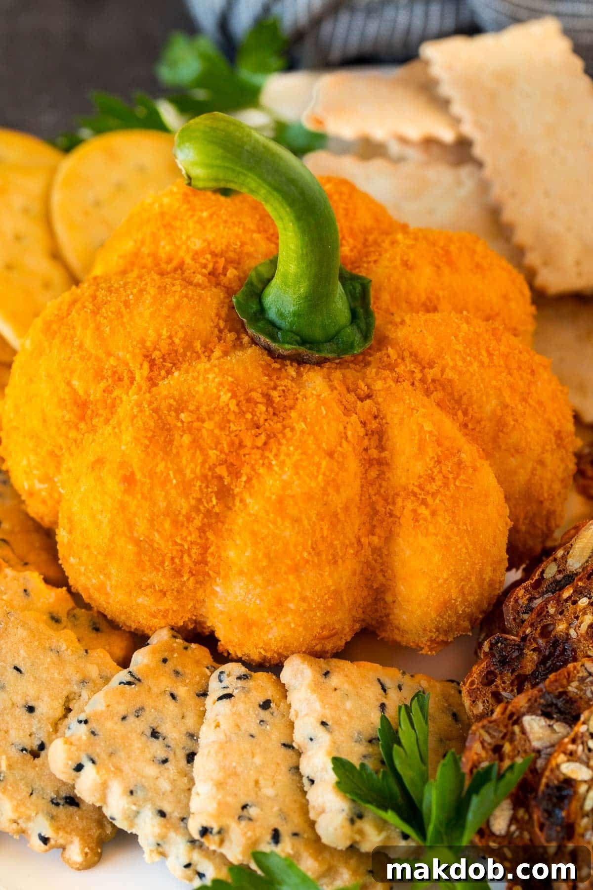 Pumpkin Spice Cheeseball 2 A pumpkin cheese ball on a serving plate surrounded by crackers.