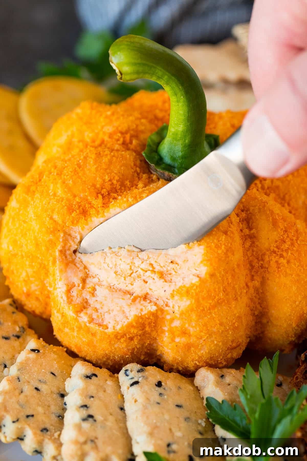 Pumpkin Spice Cheeseball 6 A knife cutting a serving of pumpkin cheese ball.