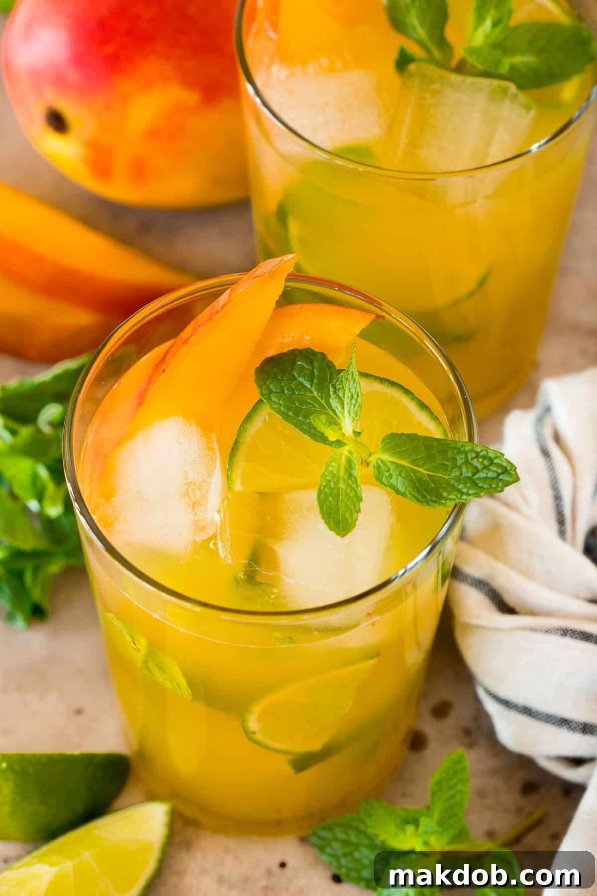 Minted Mango Oasis 6 Cups of mango mojito with ice, fresh mint and mango slices, beautifully arranged for serving.