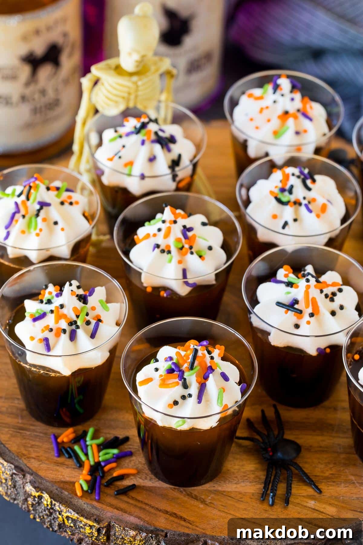 Halloween Jello shots beautifully arranged on a serving platter with generous toppings of whipped cream and colorful sprinkles.