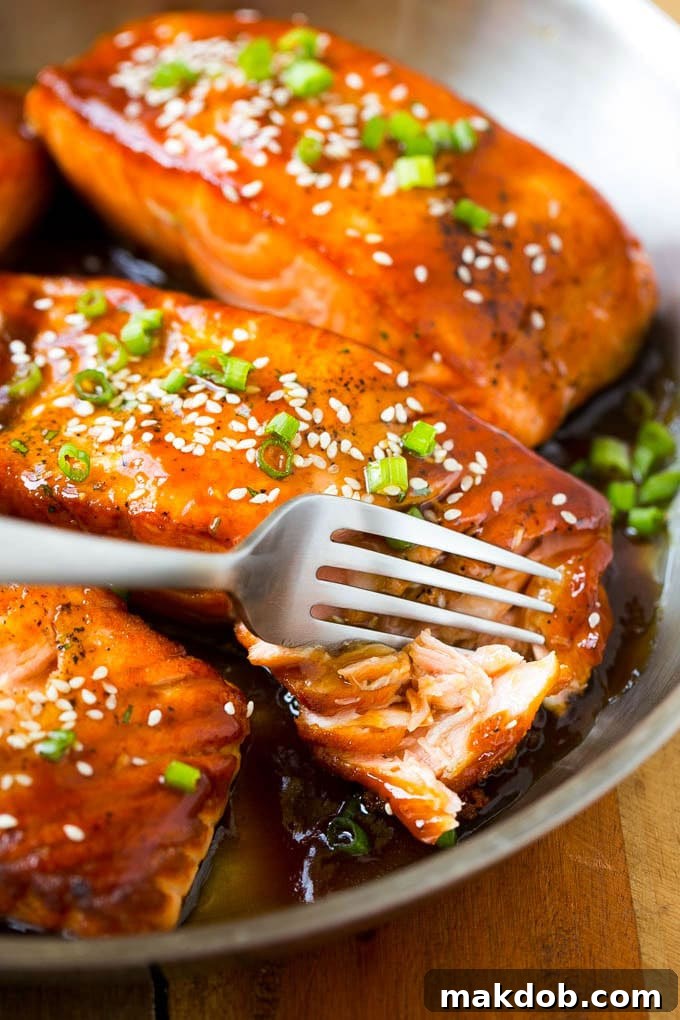 A close-up of a perfectly cooked salmon teriyaki fillet, flaking easily with a fork, showing its tender interior and glossy sauce.