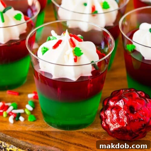 Christmas Jello shots topped with whipped cream and holiday sprinkles.