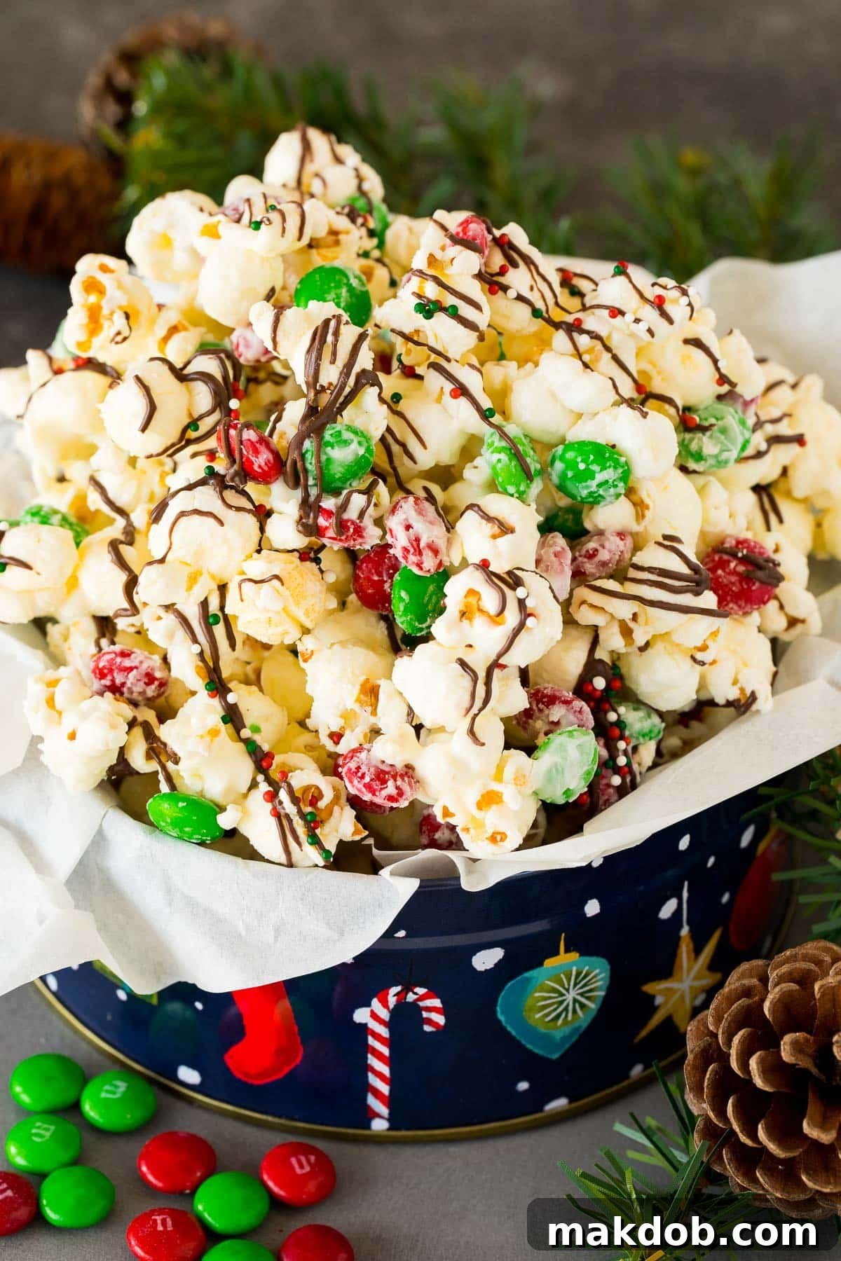 Sparkling Holiday Popcorn 2 A beautifully arranged gift tin overflowing with homemade Christmas popcorn, decorated with colorful candies and sprinkles.
