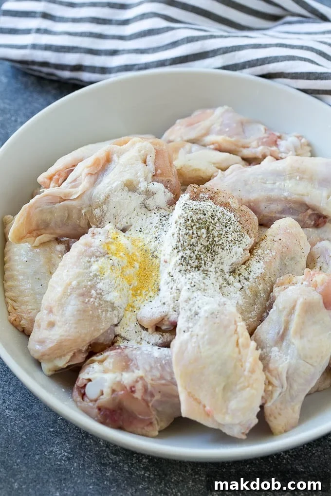 Chicken wings in a bowl with baking powder and seasonings.