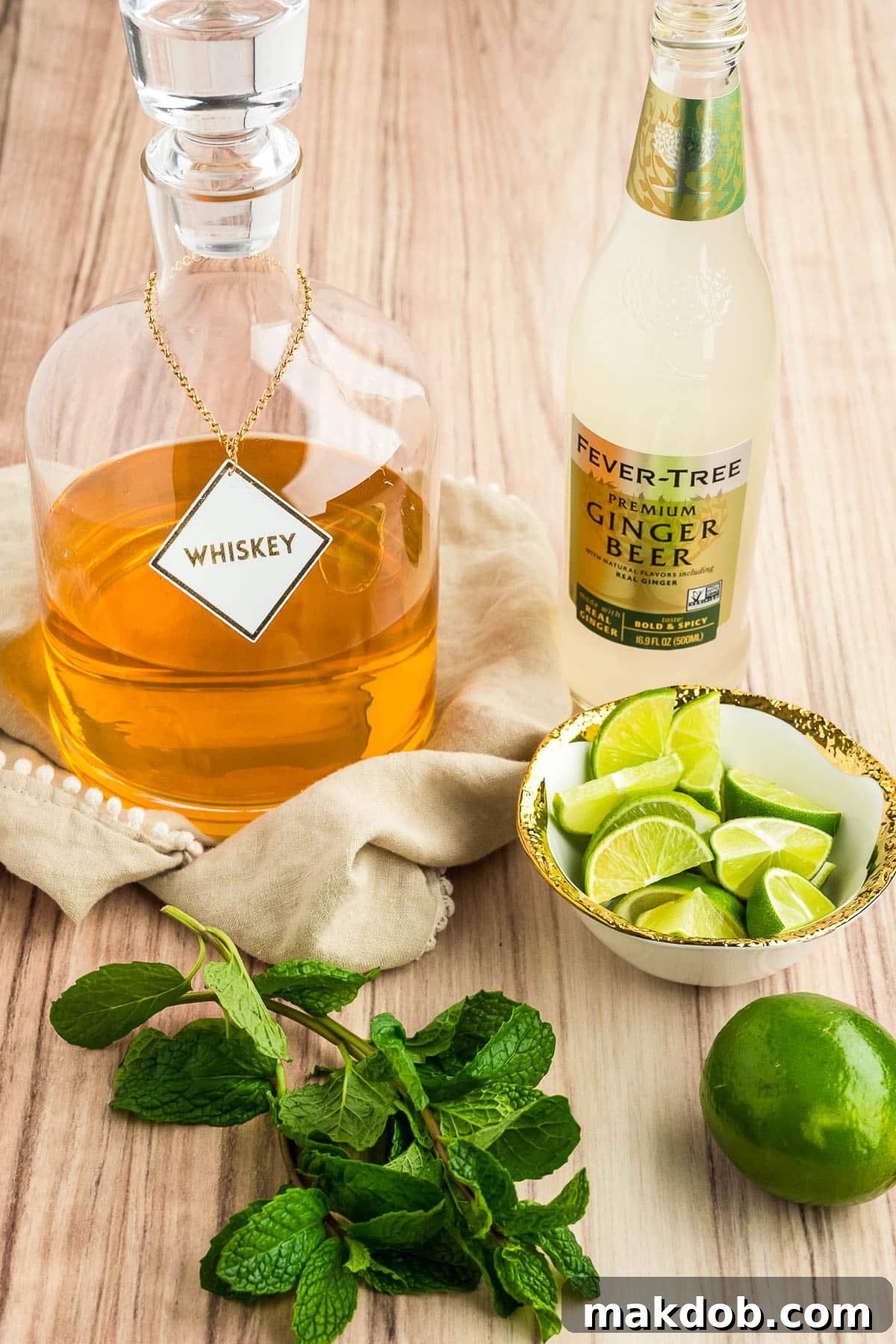 Refreshing Irish Mule 3 A flat lay image showing bottles of Irish whiskey, fresh ginger beer, whole limes, and a sprig of mint, highlighting the key ingredients for an Irish Mule.