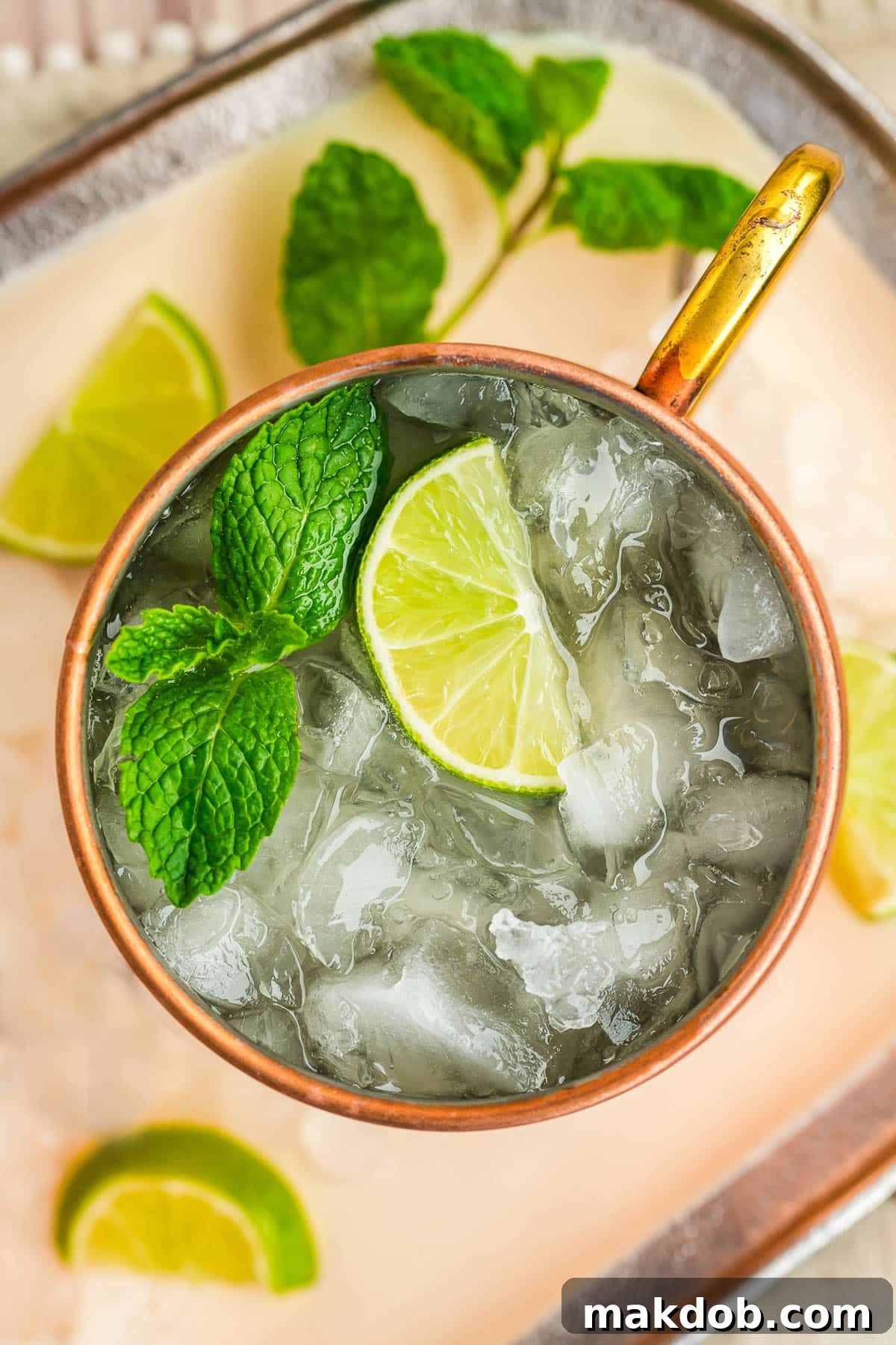Refreshing Irish Mule 5 An overhead view of an Irish mule with a copper mug filled with crushed ice and alcohol, garnished with a lime wedge and mint sprig.