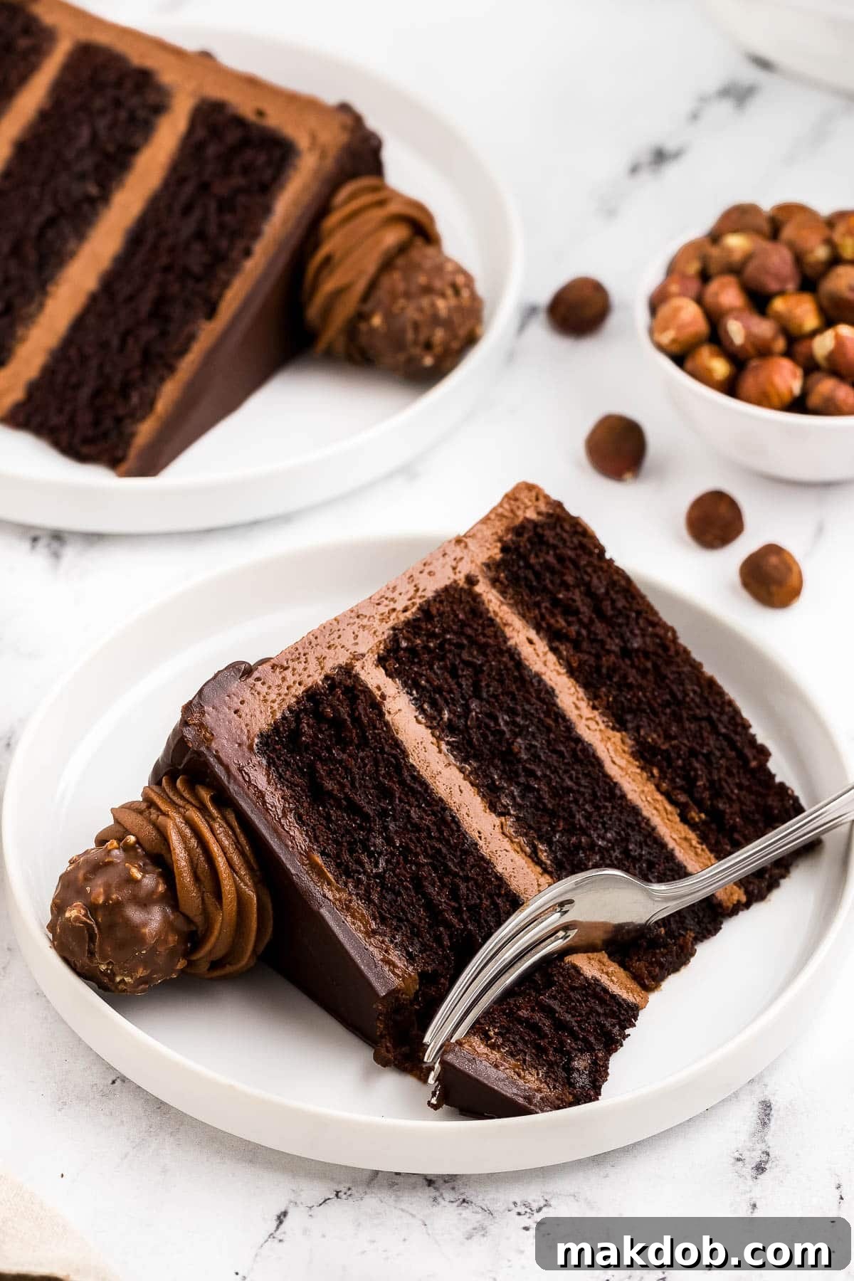 A perfectly cut slice of the layered Nutella cake, showcasing its moist chocolate layers, creamy Nutella frosting, and ganache drizzle, with a fork poised for a bite.
