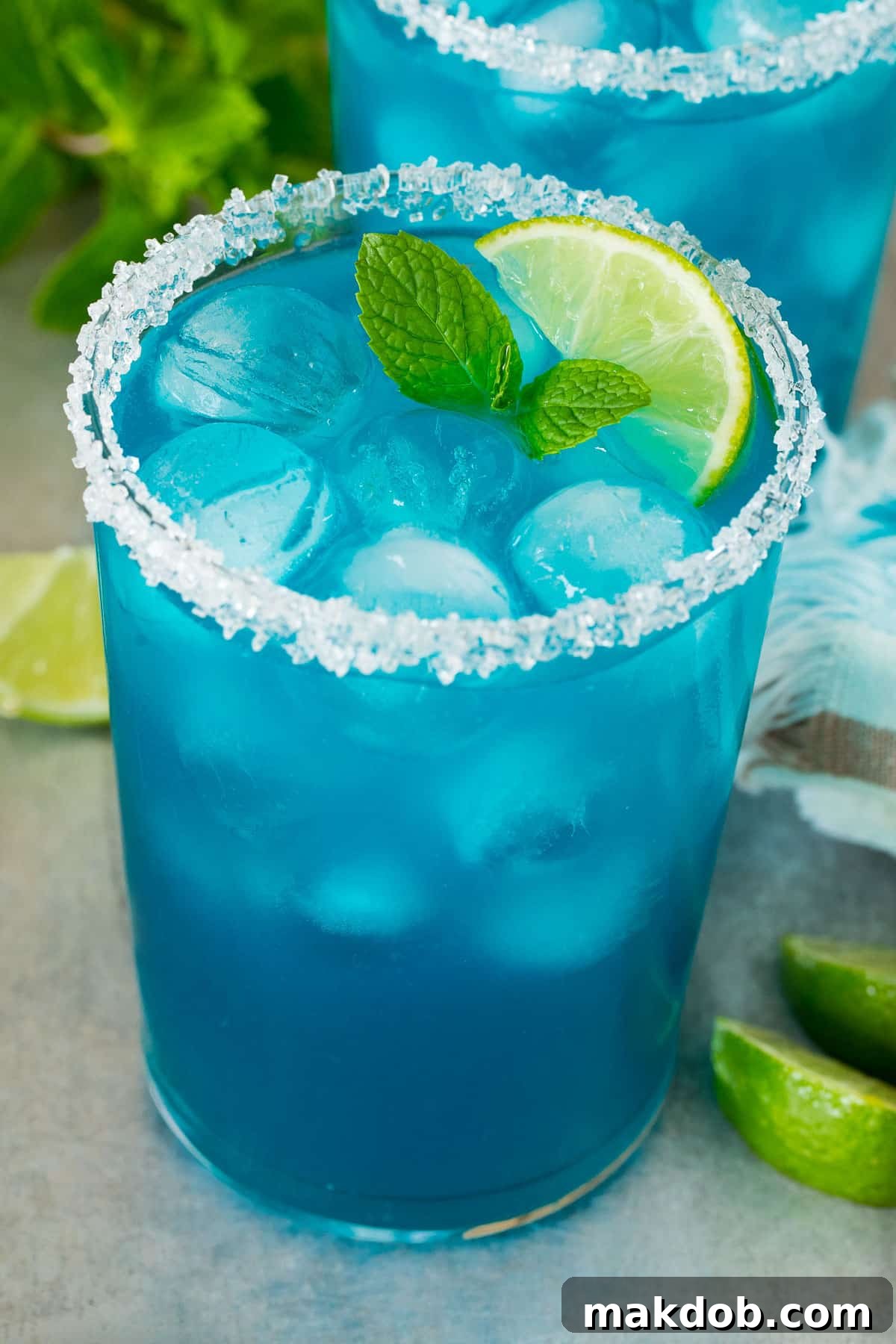 Electric Blue Margarita 6 A glass of blue margarita with a garnish of mint and lime slices.