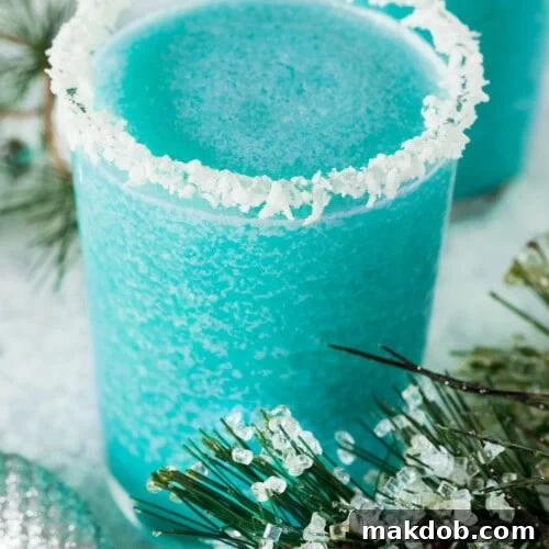 A glass of jack frost cocktail with a coconut crusted rim.