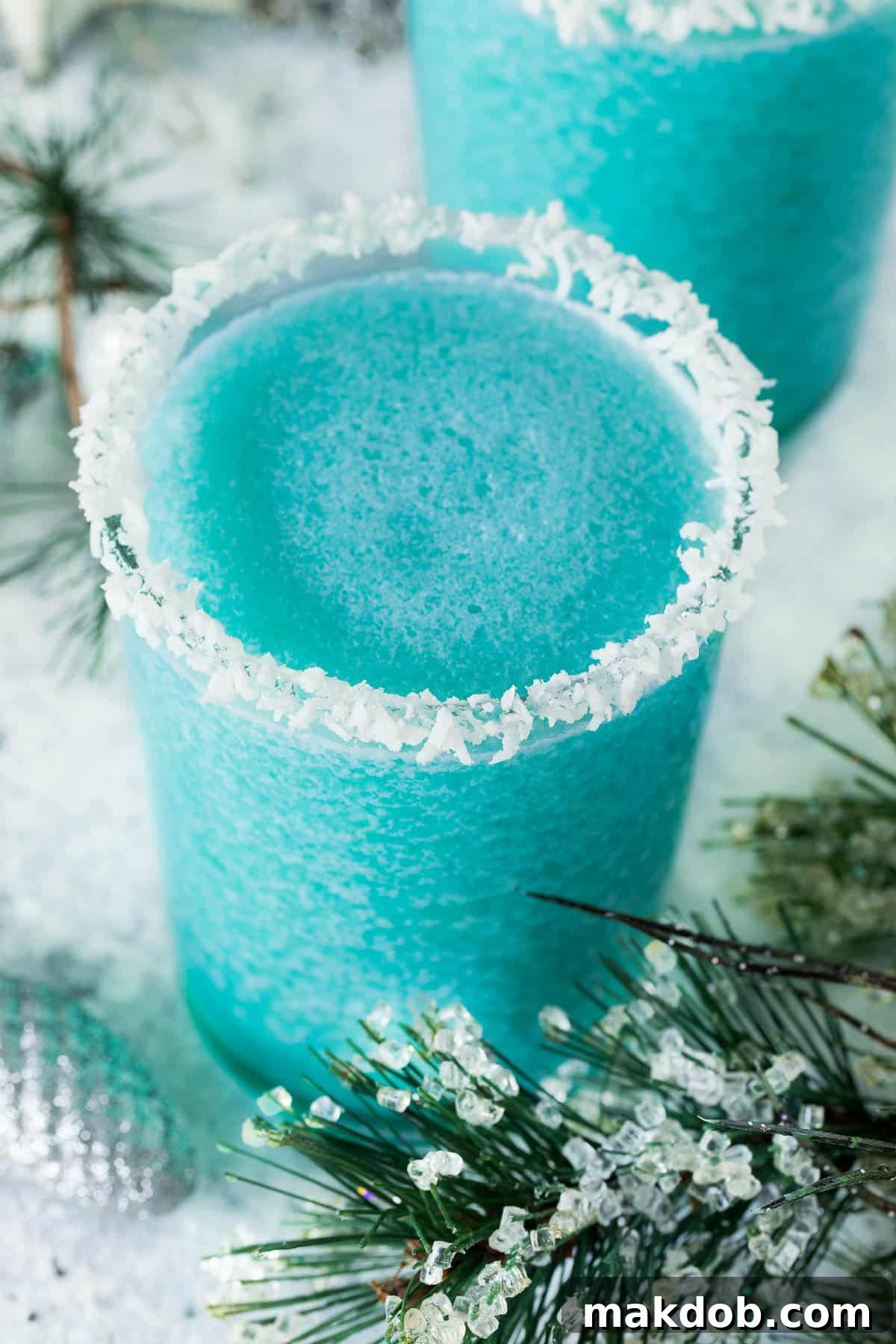A beautifully presented glass of Jack Frost cocktail surrounded by winter foliage and pinecones, highlighting its festive appeal.