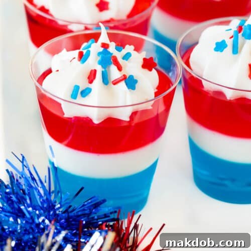 Red white and blue Jello shots topped with whipped cream and sprinkles.
