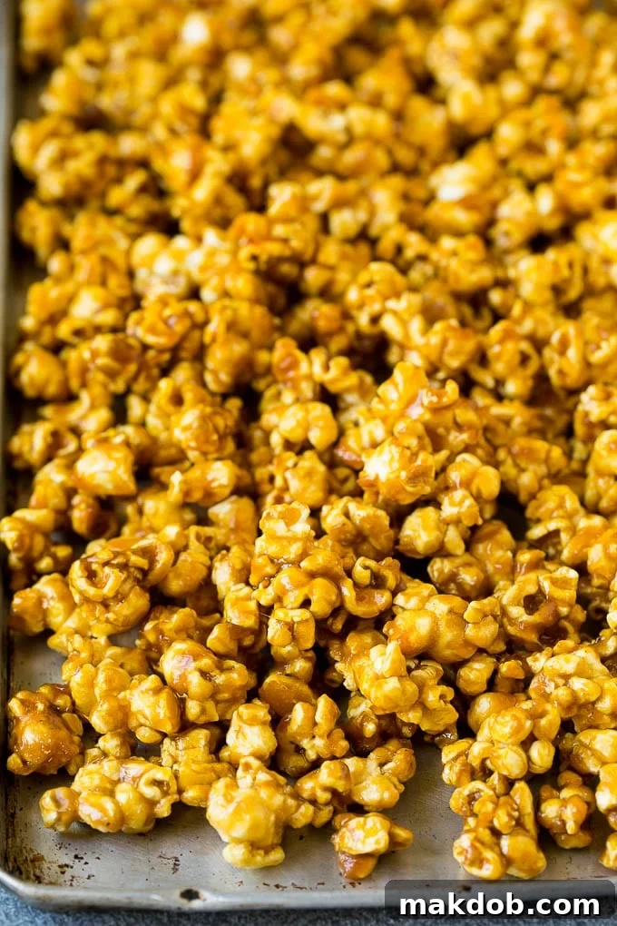 A sheet pan filled with golden, baked caramel popcorn, cooled and ready to be broken into pieces.