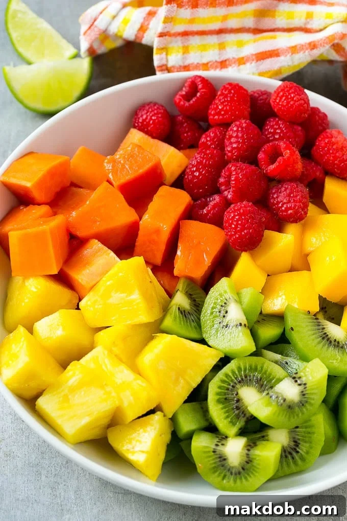 Paradise Fruit Bowl 3 A vibrant close-up of pineapple, mango, kiwi, papaya, and raspberries artfully arranged in a serving bowl, ready for the honey lime dressing.
