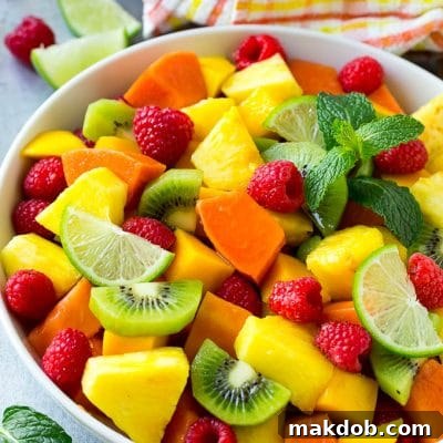Paradise Fruit Bowl 5 A vibrant bowl of tropical fruit salad, showcasing a delightful mix of mango, raspberries, papaya, kiwi, and pineapple, all glistening from the honey lime dressing.