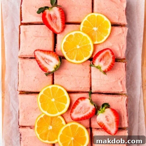 Sunshine Strawberry Lemon Cake 12 A strawberry lemon cake cut into squares and garnished with fresh berries and lemon slices.