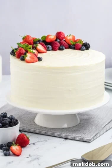Sunshine Strawberry Lemon Cake 10 An exquisite berry chantilly cake presented on a cake stand, lavishly topped with an assortment of fresh berries and delicate mint sprigs.