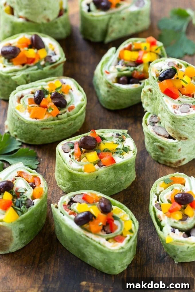 Mexican Tortilla Pinwheels | Mexican Pinwheels #pinwheels #sandwiches #tortilla #snack #dinneratthezoo A board full of Mexican tortilla pinwheels garnished with peppers and black beans.
