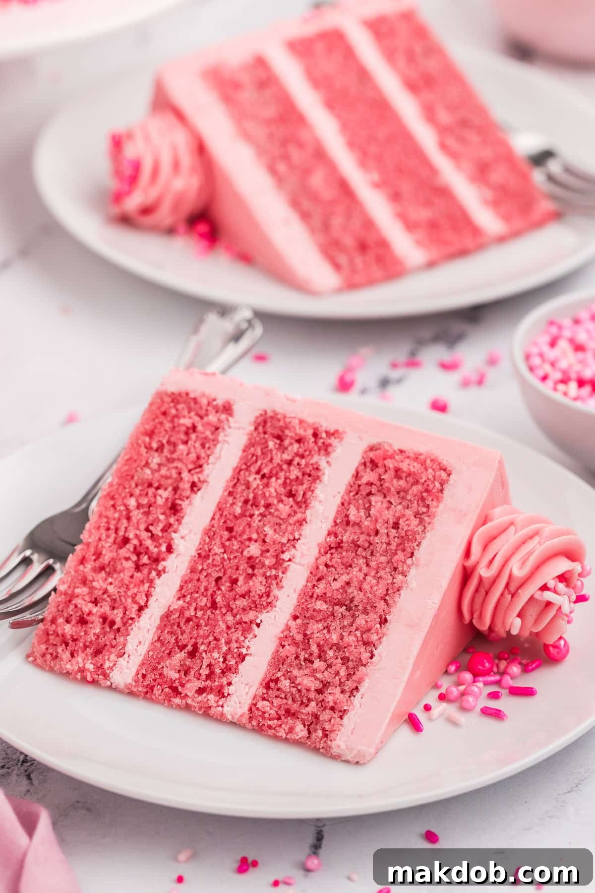 Individual slices of Pink Velvet Cake on plates, each perfectly portioned and decorated with sprinkles, ready to be enjoyed.