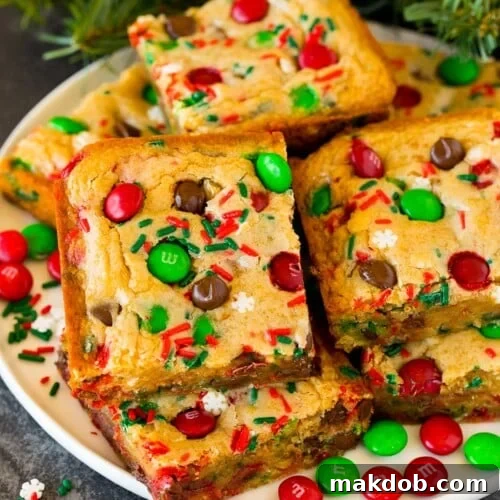 Christmas cookie bars on a plate with sprinkles and M&M candies as garnish.
