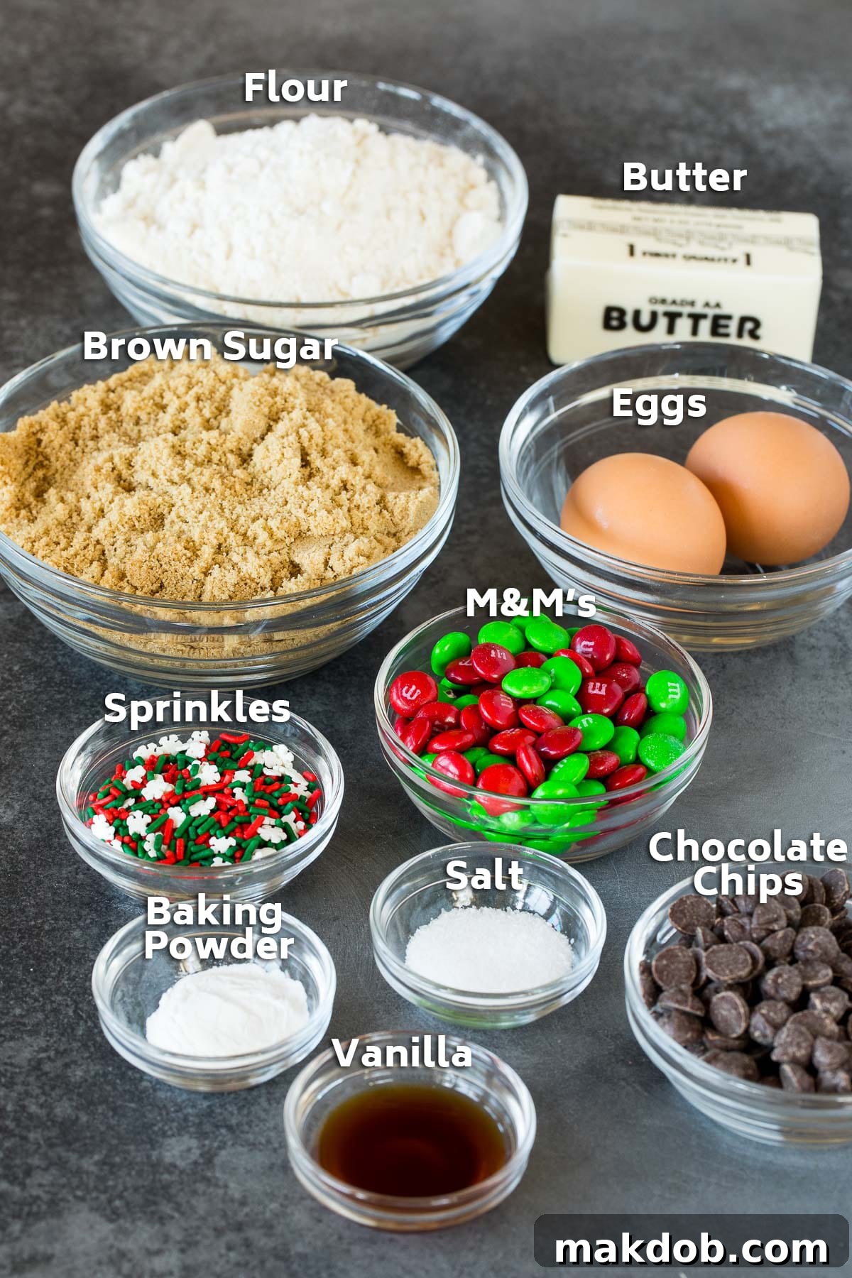 Bowls of essential baking ingredients for Christmas cookie bars, including flour, rich brown sugar, fresh eggs, aromatic vanilla extract, and colorful chocolate candies.