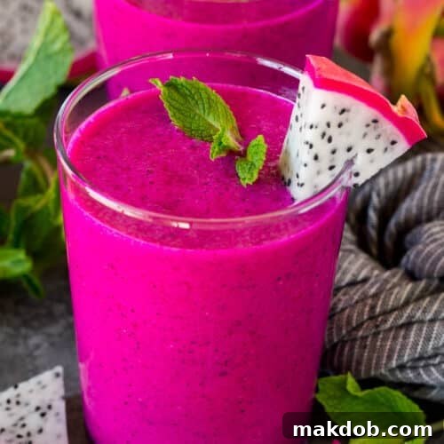 Two cups of dragon fruit smoothie topped with mint and fresh dragon fruit.