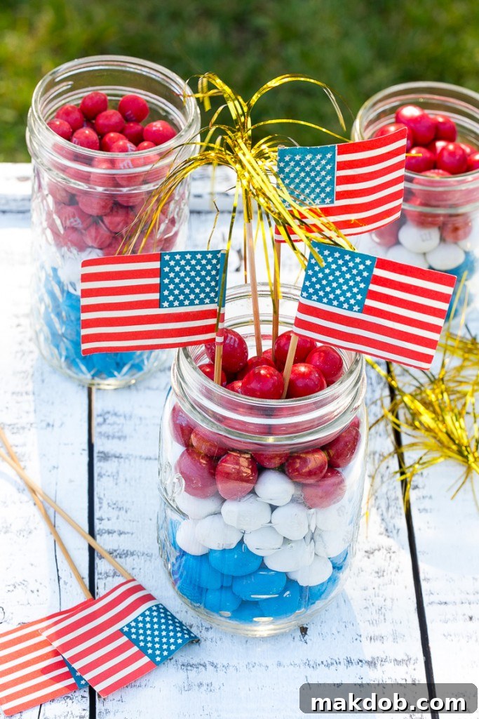 Vibrant firecracker centerpieces made with layered Red, White & Blue M&M's in glass jars, adorned with flag picks.