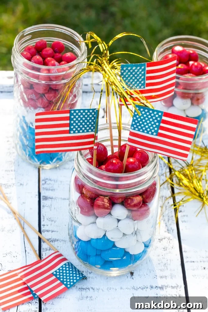 Patriotic M&M's Jar Centerpiece Ideas Festive centerpieces crafted with clear glass jars filled with layered Red, White & Blue M&M's and flag picks.