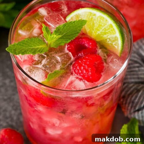 A Raspberry Mojito topped with fresh berries and a mint sprig.