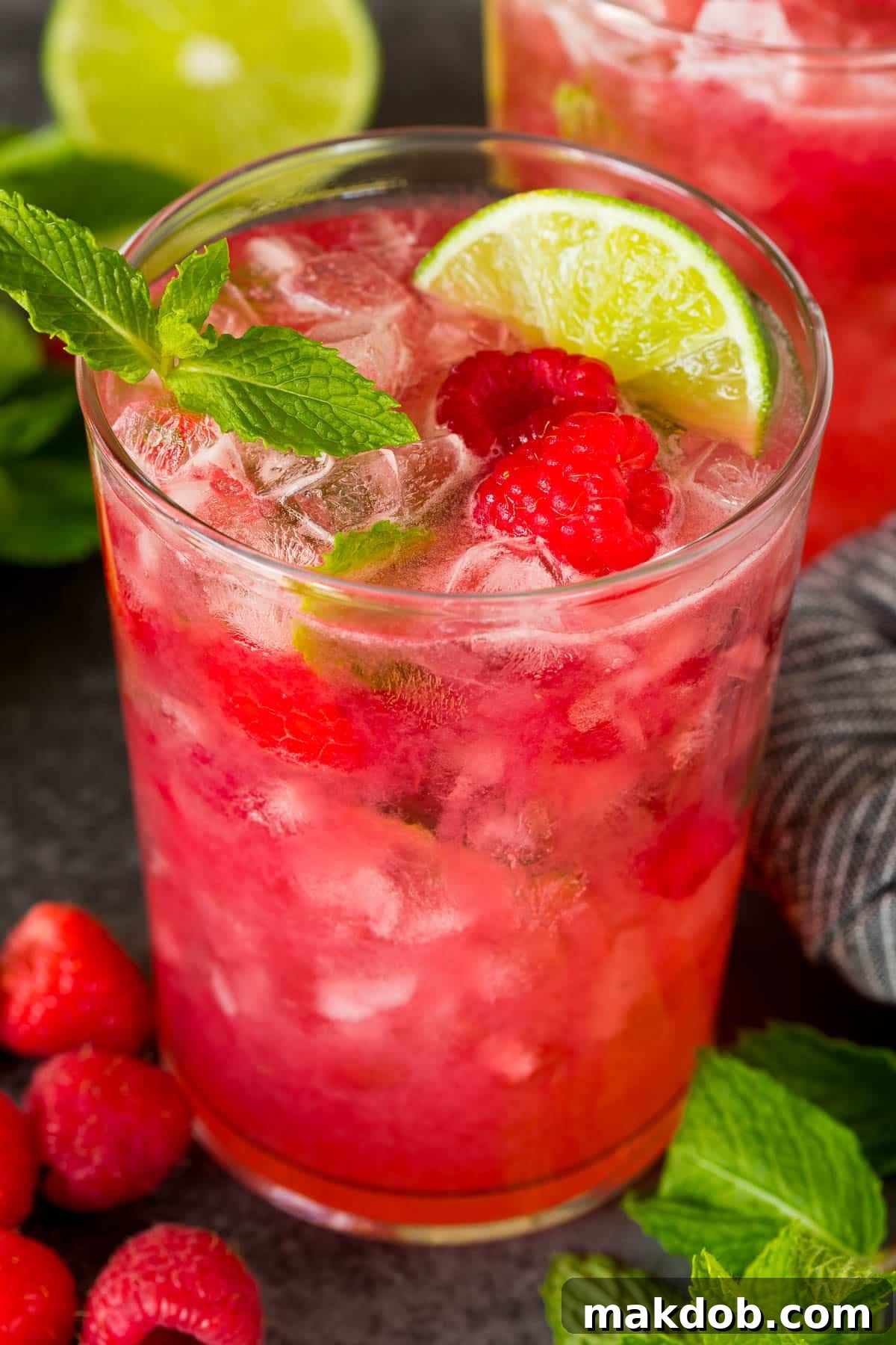 A refreshing cup of Raspberry Mojito, beautifully garnished with fresh lime slices and raspberries.