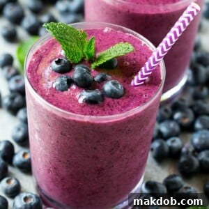 Blueberry smoothie in a glass with a straw.