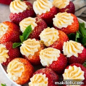A plate of cheesecake stuffed strawberries garnished with fresh mint.