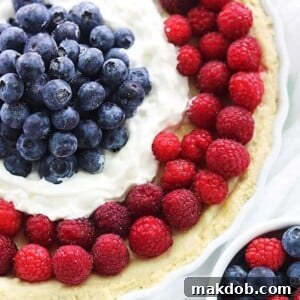 An image of a round tart decorated with blueberries and raspberries.
