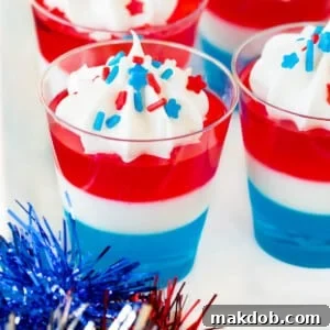 Red white and blue Jello shots topped with whipped cream and sprinkles.