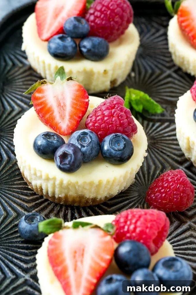 Mini Greek yogurt cheesecakes topped with fresh berries and garnished with mint.