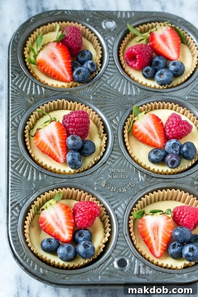 Greek yogurt cheesecakes in muffin cups garnished with fruit.