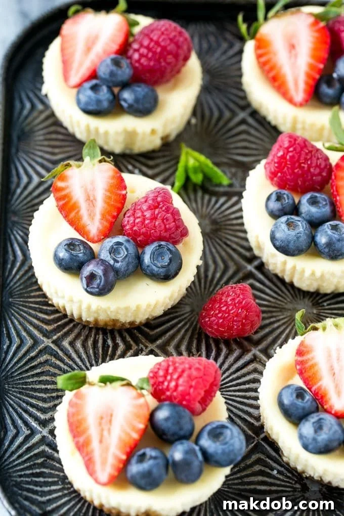 Individual Greek yogurt cheesecakes topped with blueberries and raspberries.