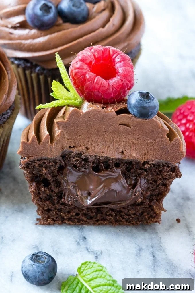 A detailed cross-section of a chocolate cupcake revealing a luscious filling of Nutella, surrounded by moist chocolate cake. Garnished with fresh berries.