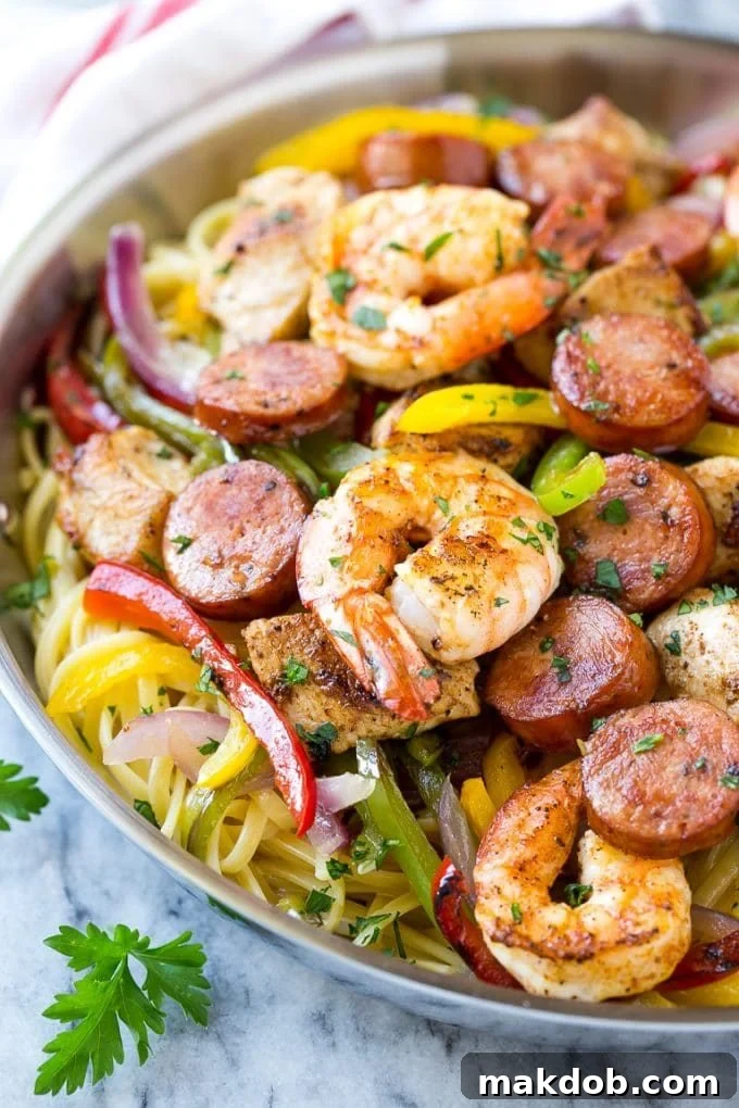 A pan filled with a colorful and hearty Cajun jambalaya pasta, featuring perfectly cooked spiced chicken, plump shrimp, sliced sausage, and vibrant bell peppers and onions, ready to be served.
